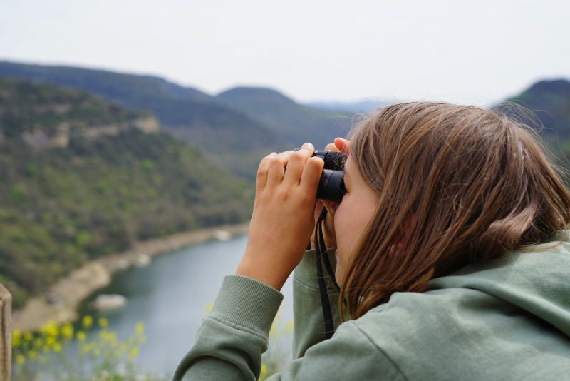 Niña con prismáticos con vistas al pantano de Sau