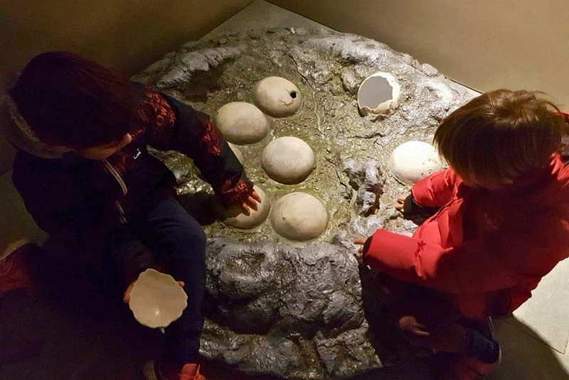 Niños pequeños tocando réplicas de huevos en el Centro de Interpretación Dinosaurios de Fumanya