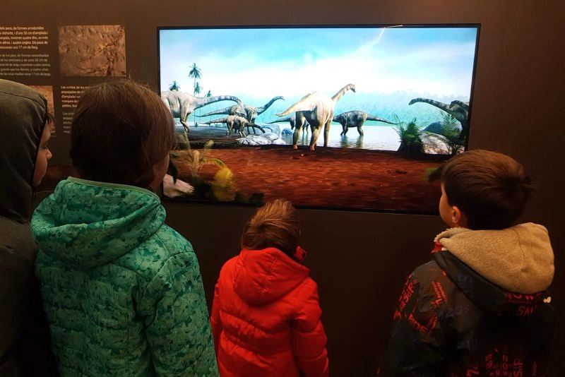 Niños pequeños atentos a los paneles explicativos del Centro de Interpretación Dinosaurios de Fumanya
